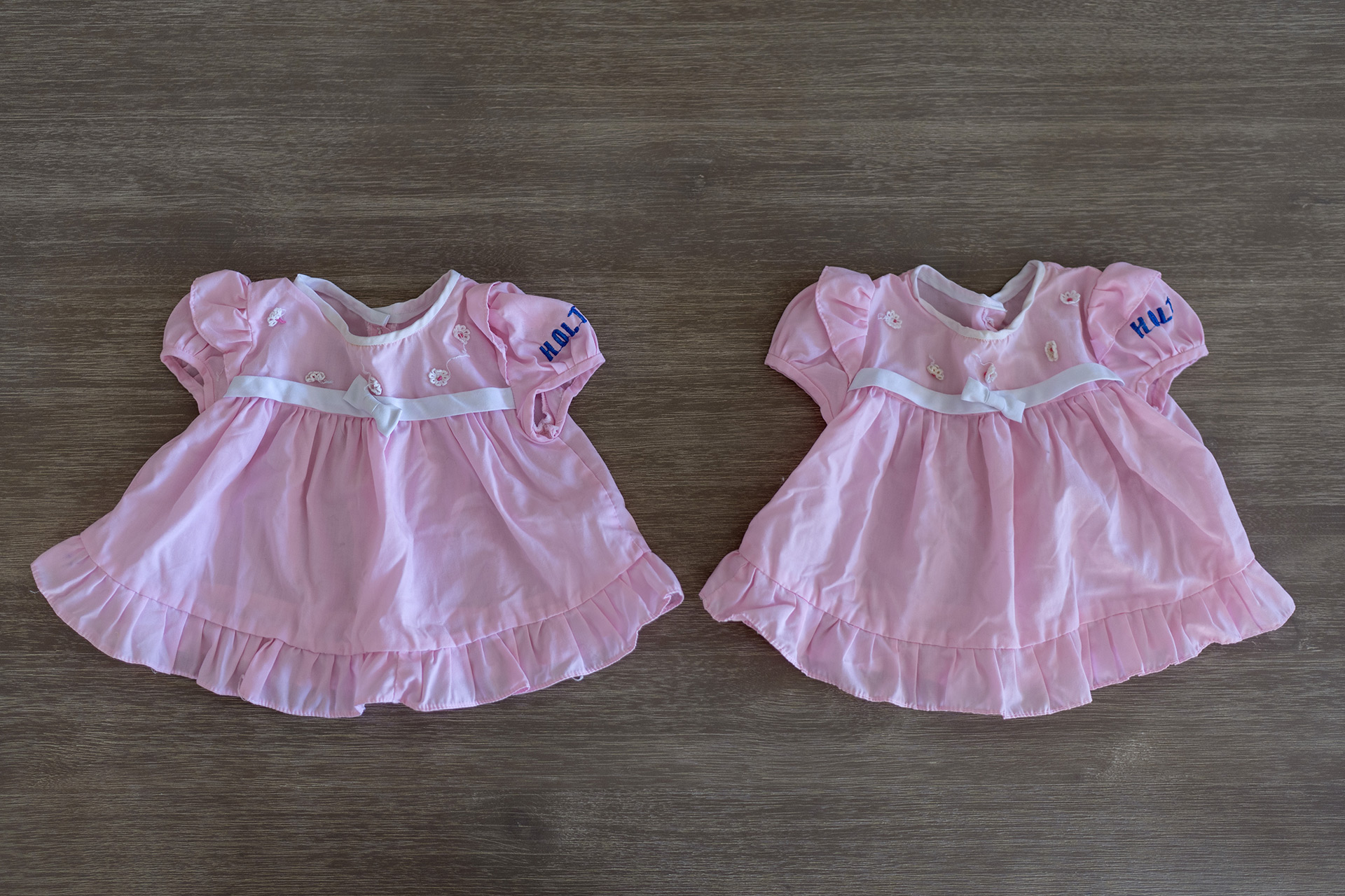 Two matching baby outfits lie on the floor.